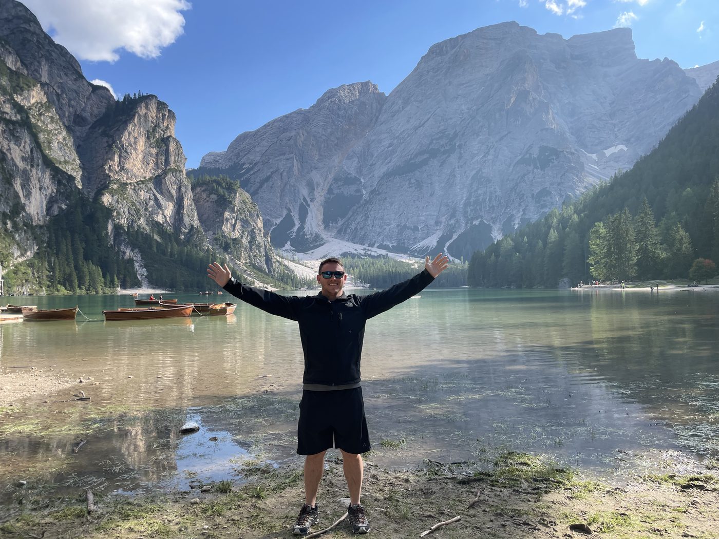 Bidwell Cranage with arms raised at Lago di Braies, a turquoise lake in the Italian Dolomites