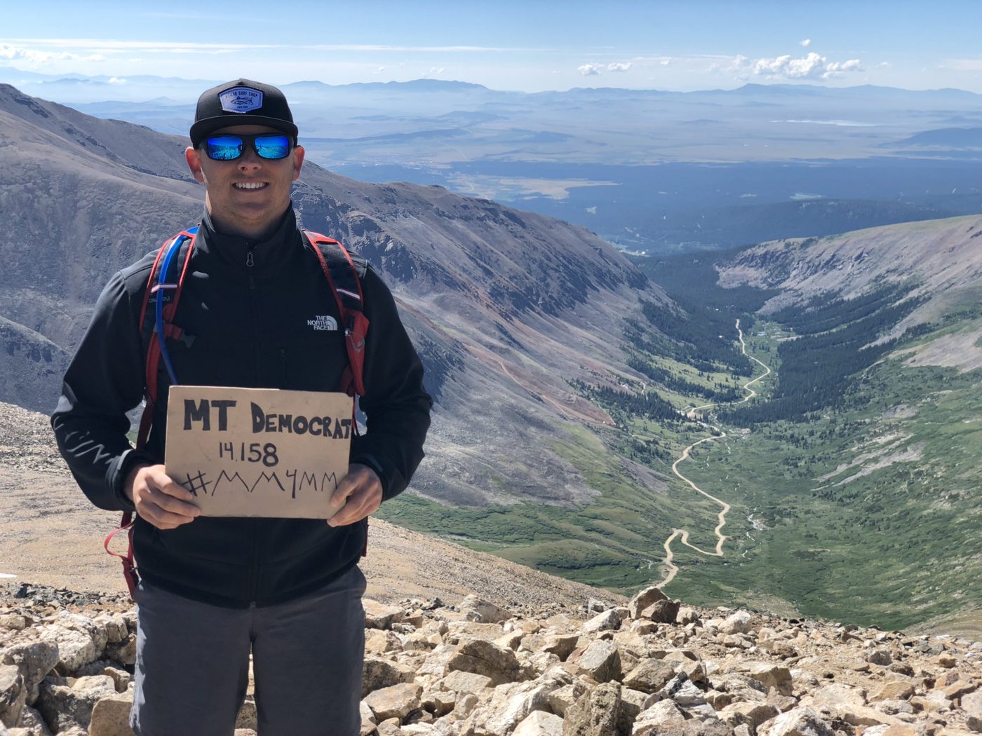 Bidwell Cranage on the summit of Mount Democrat, a Colorado fourteener, holding a summit sign